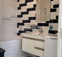 Badezimmer in einer 2-Zimmer-Wohnung mit Mosaikboden, schwarz-weißen Fliesen und Waschbecken.