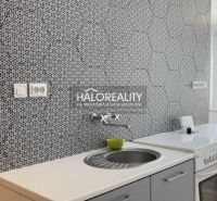 Küche mit gemusterten Fliesen und weißer Arbeitsplatte in einer 2-Zimmer-Wohnung.