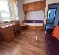 Ein Zimmer in einer 3-Zimmer-Wohnung mit Holzelementen, Schränken und einem Sofa.