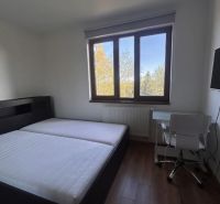 Schlafzimmer mit Bett, Tisch und Holzboden in einer 3-Zimmer-Wohnung.