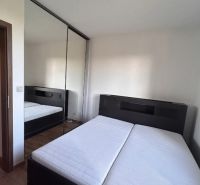 Schlafzimmer in einer 3-Zimmer-Wohnung mit einem Doppelbett, einem Spiegelschrank und einem Boden mit Holzdekor.