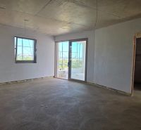 Ein Zimmer in einer 3-Zimmer-Wohnung mit einem rohen Betonboden und weißen Wänden.