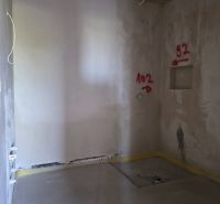 Innenraum einer 3-Zimmer-Wohnung mit verputzten Wänden und markierten Stellen für Installationen.