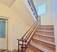 Eine Treppe in einem Einfamilienhaus mit einem Fenster aus Glasbausteinen und offenen Türen.