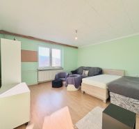 Ein Zimmer mit Betten, einem Sofa und einem Boden mit Holzdekor in einem Einfamilienhaus.