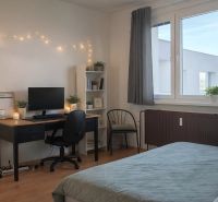 Schlafzimmer mit Tisch, Computer, Stuhl und Regal in einer 4-Zimmer-Wohnung. Boden mit Holzdekor.