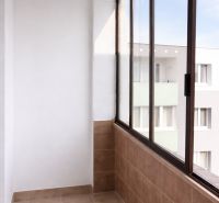 Ein verglaster Balkon in einer 4-Zimmer-Wohnung mit hellem Fliesenboden und Blick auf ein Wohngebäude.