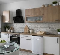 Küche in einer 4-Zimmer-Wohnung mit matten weißen und hölzernen Schränken und einem Glastisch.