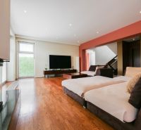 Wohnzimmer mit Kamin, Holzboden und Treppe in einem Einfamilienhaus.