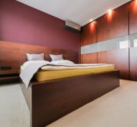 Schlafzimmer im Einfamilienhaus mit Bett, Einbauschrank und weinroter Wand.