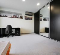 Ein geräumiges Zimmer mit einem Schreibtisch und einem großen Einbauschrank in einem Einfamilienhaus.