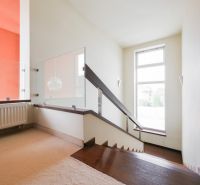 Eine Treppe mit modernem Geländer und Teppich in einem Einfamilienhaus, sonniger Raum.