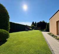Der Garten eines Einfamilienhauses in Partizánske mit gepflegtem Rasen und befestigtem Gehweg.