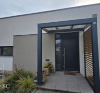 Eingang zum Einfamilienhaus in Senec mit modernem Pergola und Grünflächen.