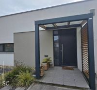 Einfamilienhaus in Senec mit minimalistischer Fassade, Eingangstüren und Pergola.