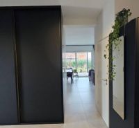 Der Flur im Einfamilienhaus mit schwarzen Schränken führt ins Wohnzimmer.