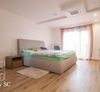 Schlafzimmer mit Bett, Kommode, Nachttischen und Holzboden in einem Einfamilienhaus.