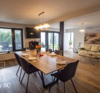 Wohnzimmer mit Holzboden in einem Einfamilienhaus, eingerichtet mit Esstisch und Sofa.