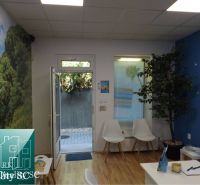 Innenraum eines Einfamilienhauses mit blauer Wand, weißen Stühlen und einem Boden in Holzoptik.