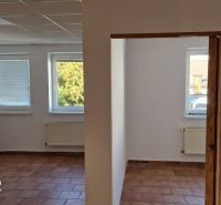 Innenraum eines Einfamilienhauses mit Terrakottaboden, weißen Wänden und Heizkörpern unter den Fenstern.