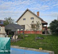 Ein Einfamilienhaus in Turany mit Rasen, Pavillon und einem Außenkamin im Garten.