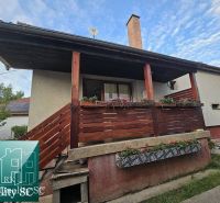 Ein Einfamilienhaus in der Gemeinde Tureň mit einem Holzgeländer und Blumendekoration auf der Veranda.