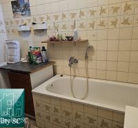 Ein Badezimmer mit Badewanne in einem Einfamilienhaus, gefliest mit Blumenmuster.