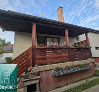 Das Einfamilienhaus in der Straße in Turna hat einen Holzbalkon mit Blumenschmuck.