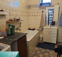 Badezimmer im Einfamilienhaus mit Badewanne, Schrank und Fliesen an den Wänden.