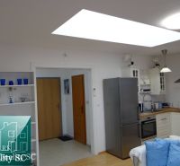 Küche in einer Einzimmerwohnung mit Holzboden und hellen Schränken.