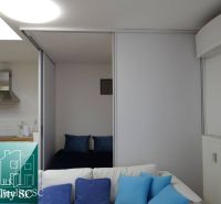 Wohnbereich in einer Einzimmerwohnung mit Kochnische und blauen Accessoires.