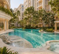 Luxuriöser Pool mit Liegestühlen, umgeben von Grünflächen, beim Bau von Wohnungen in Pattaya.
