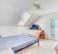Ein Schlafzimmer im Dachgeschoss eines Einfamilienhauses mit einfacher Einrichtung und Dachfenster.