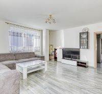 Wohnzimmer in einem Einfamilienhaus mit einer Eckcouch und einem Boden in Holzoptik.