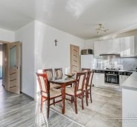 Eine Küche in einem Einfamilienhaus mit Keramikfliesen, einem Holztisch und weißen Schränken.