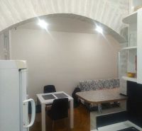 Küche in einer 2-Zimmer-Wohnung mit Backsteinbogen, Tisch und Stühlen, Boden mit Holzdekor.