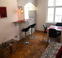 Wohnzimmer einer Zweizimmerwohnung mit Holzboden, Bar und Esstisch.