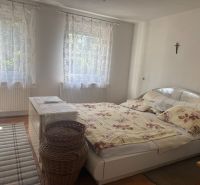 Schlafzimmer in der Hütte mit Bett, Teppich, weißer Kommode und Vorhängen, Boden mit Holzdekor.