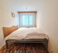 Schlafzimmer in einer 2-Zimmer-Wohnung mit Doppelbett und Boden in Holzoptik.