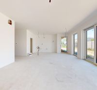 Einfamilienhaus mit großen Fenstern und Blick in den Garten, weiße Wände, heller Boden.