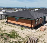Das Äußere eines Einfamilienhauses in Bernolákovo in der Rohbauphase mit einem ungestalteten Garten.