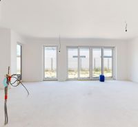 Geräumiges, unmöbliertes Interieur eines Einfamilienhauses mit großen Fenstern.