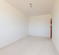 Ein leerer Raum in einem Einfamilienhaus mit weißen Wänden und ohne Bodenbelag.