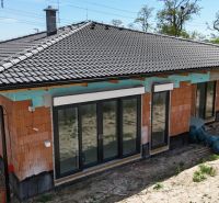 Ein Einfamilienhaus im Bau in Bernolákovo mit einem Keramikdach und französischen Fenstern.