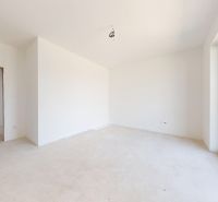 Innenraum eines Einfamilienhauses mit weißen Wänden und einem großen Fenster.