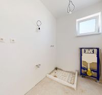 Unvollendetes Badezimmer in einem Einfamilienhaus mit Vorbereitung für Installationen und einem Fenster an der Wand.