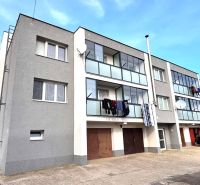 Ein dreistöckiges Wohnhaus mit Balkonen und Autos in Hlboké.