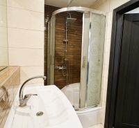 Badezimmer mit Badewanne, Dusche und dunkler Tür in einer 4-Zimmer-Wohnung.