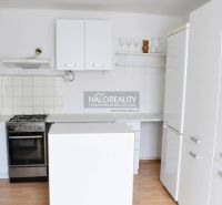 Küche in einem Einfamilienhaus mit weißen Schränken und einem Boden in Holzoptik.