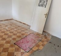 Ein Raum in einer Hütte mit einem Kachelboden und Türen ohne Scharniere.